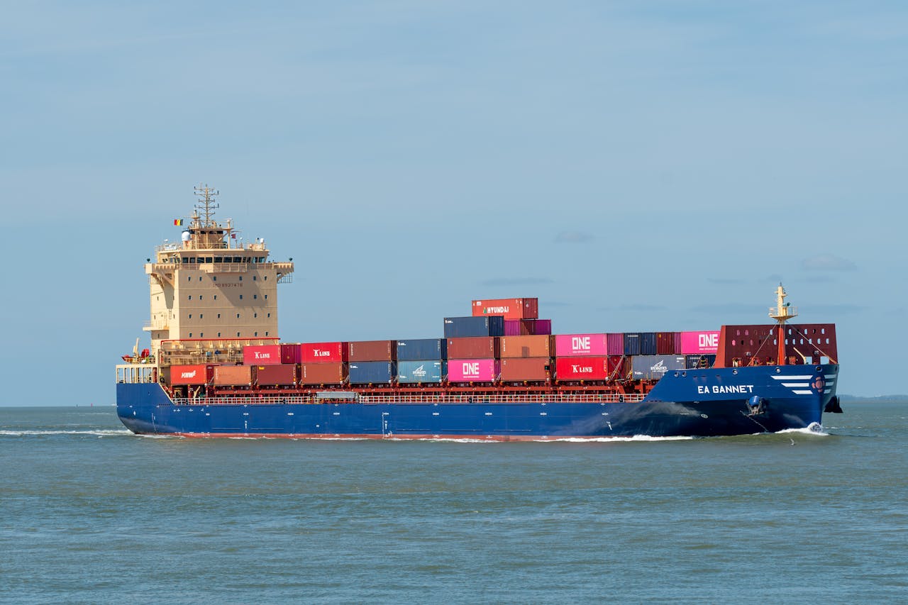 A cargo ship transporting colorful containers across a calm sea on a clear day.