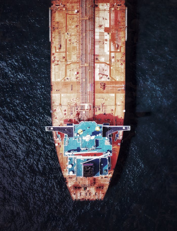 Top-down aerial photo of a large cargo ship navigating the open sea, highlighting the vessel